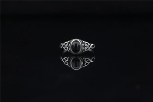 Macro detail of vintage silver-tone ring with black gemstone and filigree patterns