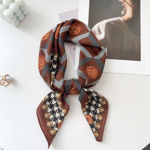 Detailed close-up of a vintage silk scarf featuring checkered patterns and rose motifs