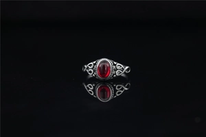 Detail of vintage silver ring featuring an oval red gemstone and carved scrollwork
