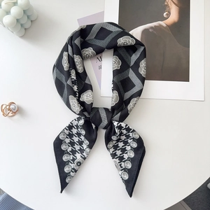 Detail of rose and checkerboard pattern silk scarf tied in a bow with pearl accessories