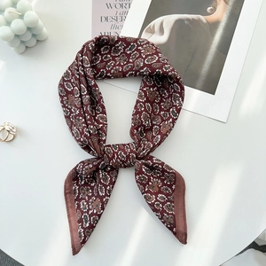Close-up of deep red paisley silk scarf styled as a bow on an elegant white background