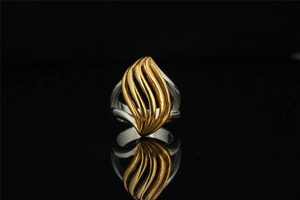 Close-up of dual-tone silver and gold ring with wavy leaf-shaped flame texture design