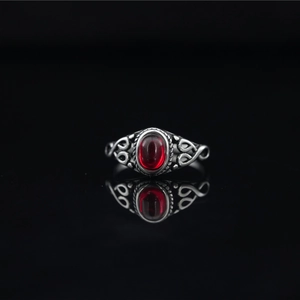 Vintage oxidized silver ring featuring an oval red gemstone and intricate filigree patterns