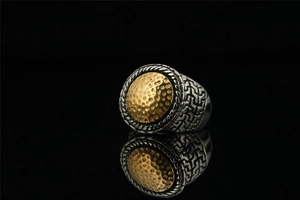 Macro detail of retro signet ring with golden hammered texture and braided steel edges