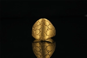 Macro detail of gold textured ring with pebble pattern and matte brushed finish surface