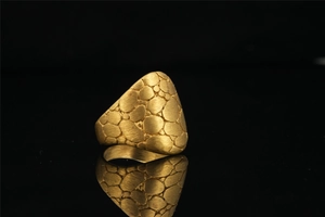 Macro shot of gold punk ring featuring irregular pebble texture and brushed metal finish