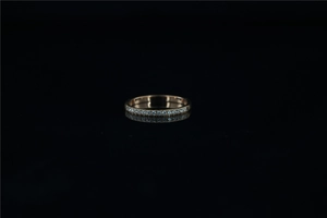 Detail of rose gold eternity ring with small sparkling diamonds on a black background