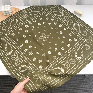 Detail showing the olive green paisley silk square scarf with soft fabric texture