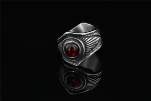 Dettaglio anello in acciaio vintage con trama ad ala di aquila e pietra rossa centrale