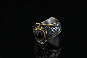 Dettaglio ravvicinato di un anello vintage in acciaio con gemma nera e piume incise