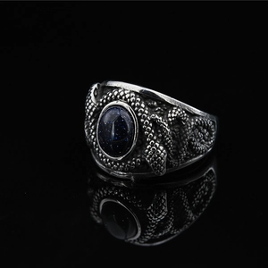 Bague vintage en acier titane avec pierre bleue ovale et texture écaillée sur fond noir