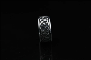 Macro detail of silver ring with intricate Celtic Knot pattern on a black background
