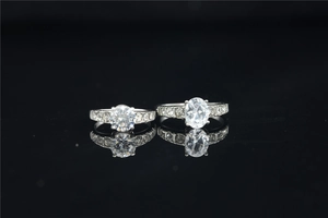 Macro detail of round and oval cut moissanite rings with pavé diamonds on black mirror