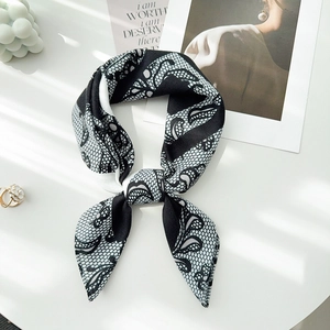 Detail of a chic black lace floral scarf tied in a bow on a stylish white setup
