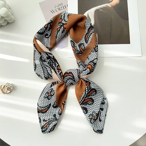 Close-up of elegant silk-like scarf with butterfly pattern tied in a bow on a white table