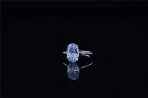 Macro shot of oval-cut light blue gemstone ring with classic silver four-prong setting