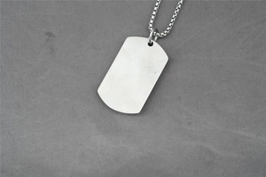 Detail of brushed silver military dog tag pendant with stainless steel box chain