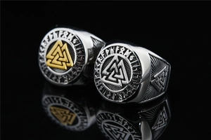 Macro view of Viking Valknut rings in silver and gold steel with Norse runes relief
