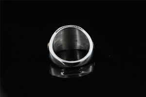 Vue macro d'une bague large en acier inoxydable avec reliefs dorés sur les côtés