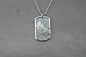 Detail of hip-hop square pendant featuring embossed eagle wings on dotted texture