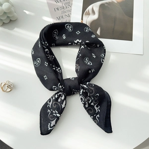 Gros plan d'un foulard en soie à motif paisley noir noué en nœud élégant