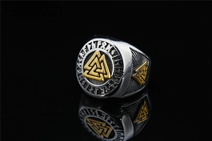 Macro detail of men's Viking ring with golden Valknut symbol and Norse runes engraving