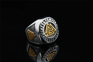 Macro shot of Viking Valknut ring featuring gold Nordic runes and silver stainless steel