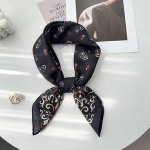 Détail d'un foulard en soie synthétique à motif paisley noué en nœud sur un bureau