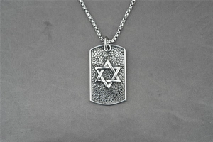 Macro detail of silver steel dog tag pendant with textured Star of David and box chain