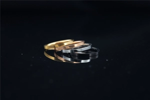 Macro shot of a four-piece minimalist titanium steel ring set in gold, rose gold, silver, and black
