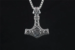 Detailed view of vintage Viking Thor's hammer pendant with Valknut knot and intricate carvings