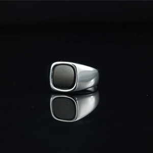 Bague vintage avec pierre noire carrée en acier inoxydable argenté sur fond noir réfléchissant