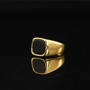 Bague vintage en acier titane doré avec pierre carrée noire sur fond miroir
