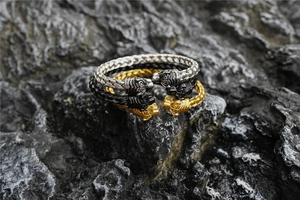 Close-up of twisted titanium steel bracelets with beast head terminals on volcanic rock