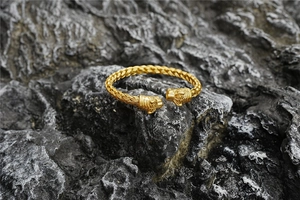 Detailed view of twin lion heads on a gold braided titanium steel twisted bangle