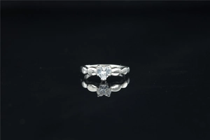 Foto macro de anillo de moissanita con forma de corazón plateado sobre superficie negra