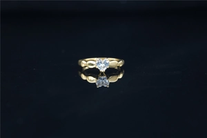 Detalle de anillo de moissanita con forma de corazón dorado y diseño de banda perlada