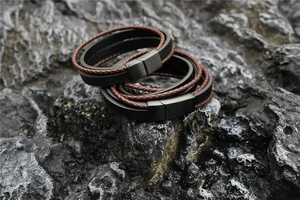 Close-up of multilayer leather bracelets with magnetic clasps on dark volcanic rock
