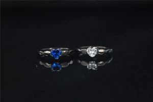 Detalle de anillos de moissanita con corazón azul y blanco en bandas negras perladas