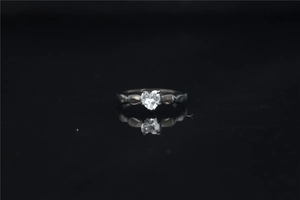 Detalle de anillo de moissanita con corte de corazón en metal vintage oscuro y reflejo