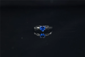Detalle de anillo de moissanita con forma de corazón y banda plateada grabada