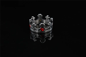 Macro di un anello a corona d'argento con pietre rosse e incisioni a croce