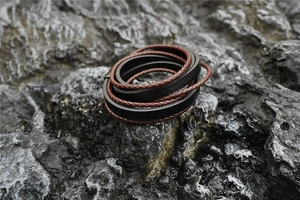 Detail view of multi-layer leather bracelet with magnetic clasp on a grey rock surface