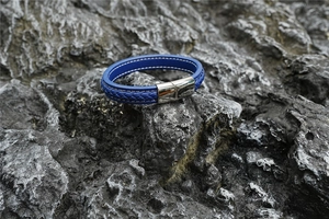Detail eines geflochtenen blauen Lederarmbands mit magnetischem Edelstahlverschluss auf Stein