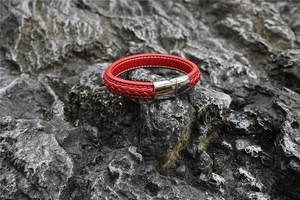Detail eines roten Lederarmbands mit silbernem Magnetverschluss auf dunklem Felsgrund