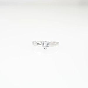 Elegante anillo de moissanita con forma de corazón plateado sobre fondo de espejo blanco
