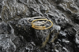 Vue détaillée de bracelets torsadés en or et argent sur fond de roche noire mate