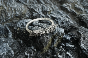 Détail des têtes de dragon sur bracelet jonc torsadé en acier de style vintage