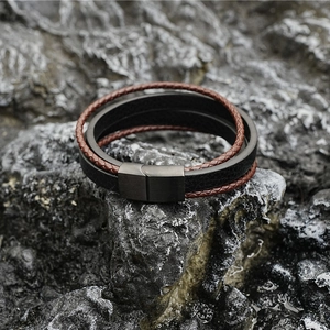 Multilayer leather bracelet with black magnetic clasp on a textured black stone rock