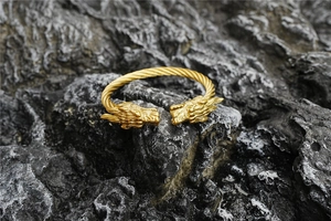 Détail du bracelet tête de dragon doré avec texture de câble torsadé sur roche sombre
